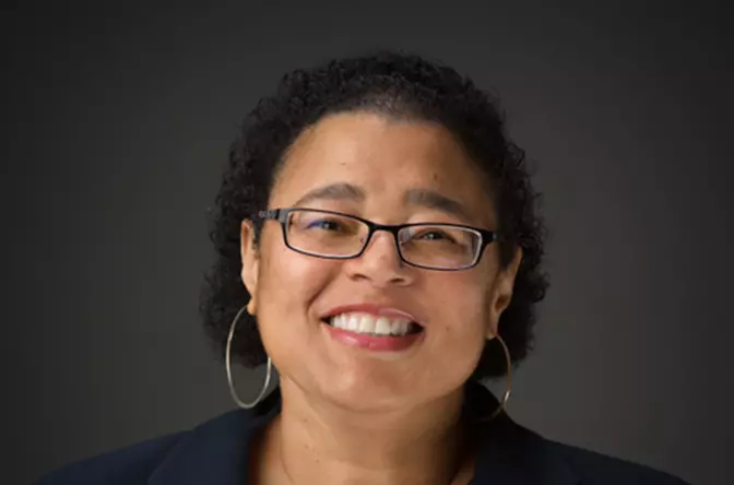 A woman with glasses smiling for the camera.